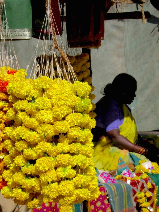 Carefully lace flowers together to sell as offerings at temple, Pune, India